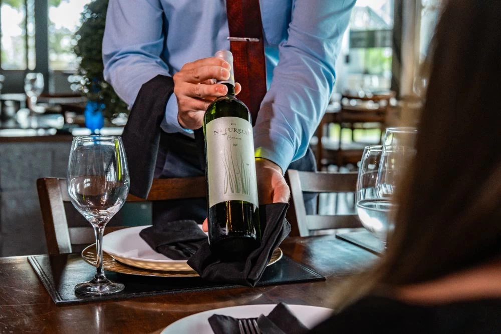 Garçom segurando uma garrafa de vinho
